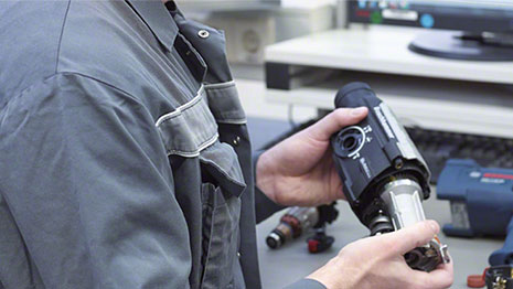 ชายคนหนึ่งถือเครื่องมือสีดำ Bosch Professional ในมือ