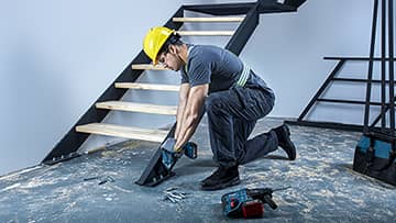 ช่างฝีมือที่สวมหมวกกำลังทำงานที่บันไดด้วยเครื่องมือ Bosch.