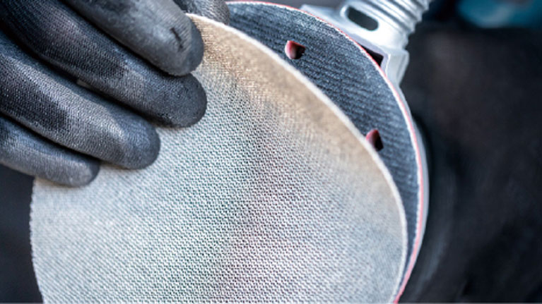 สองมือที่สวมถุงมือสีดำถือจานขัด.