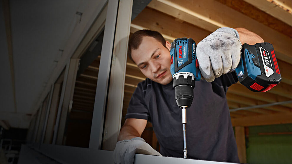 ชายคนหนึ่งที่มีสว่านไร้สาย Bosch Professional กำลังประกอบโปรไฟล์โลหะ.