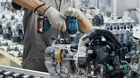 คนงานที่สวมหมวกกันน็อคและหน้ากากกำลังใช้เครื่องมือ Bosch Professional.