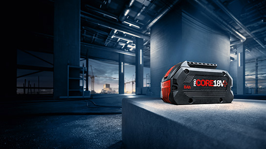 แบตเตอรี่ Bosch Professional สีดำบนบล็อกคอนกรีตสีเทาที่ไซต์ก่อสร้าง.