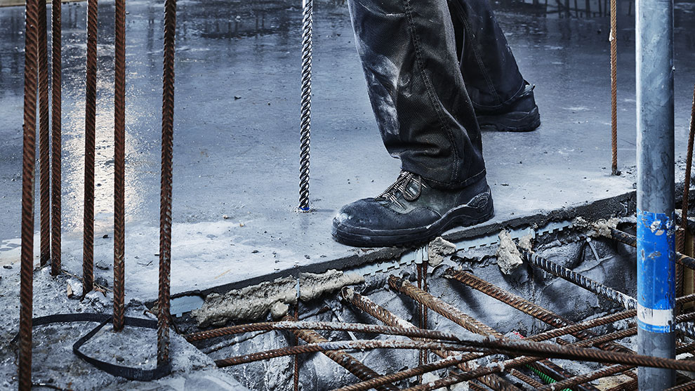 คนงานในรองเท้าบู๊ตสีดำยืนอยู่บนพื้นคอนกรีต.