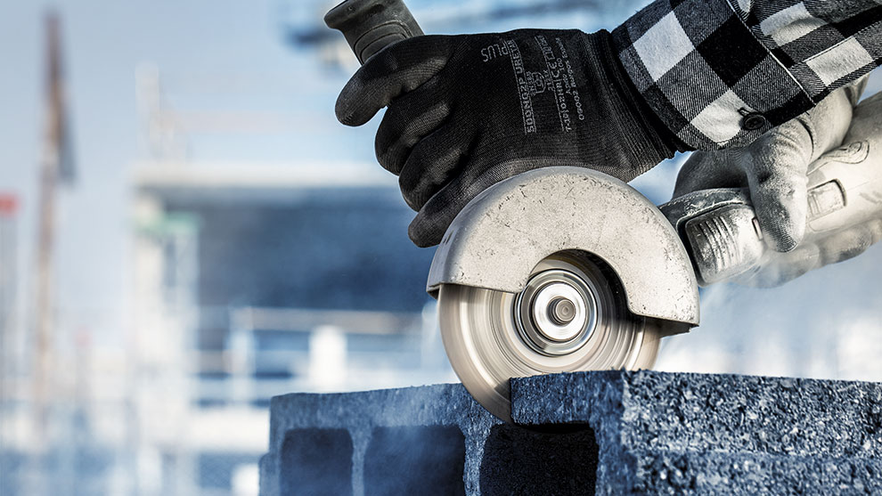 บุคคลหนึ่งกำลังตัดหินสีเทาด้วยเครื่องตัด.